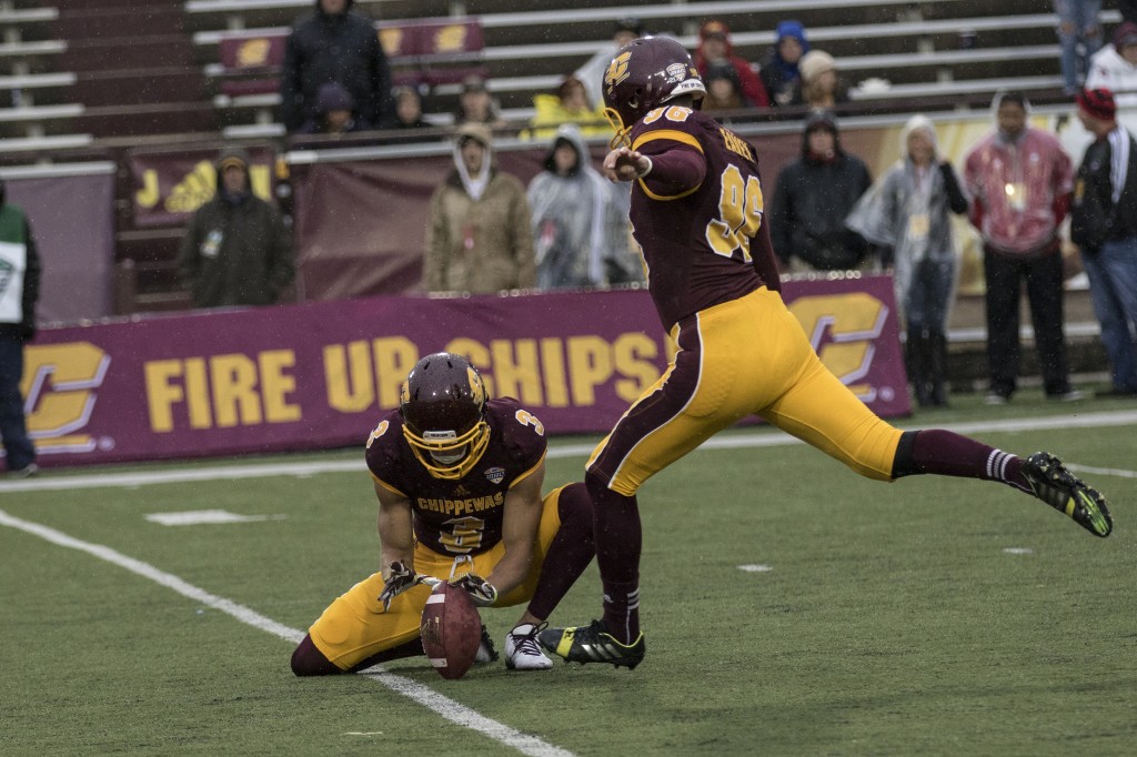 Mark Chapman, 3, holds the football for kicker Brian Eavey, 96, during the football game against Northern Illinois University on the campus of Central Michigan University, Mt. Pleasant, MI, Sunday, October 3, 2015.