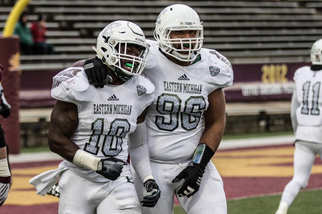 Great Ibe, 10, celebrates with Mike Brown, 96, after Ibe laid a big hit during the game at Kelly / Shorts Stadium on the campus of Central Michigan University, Mt. Pleasant, Michigan, Friday, November 27, 2015.