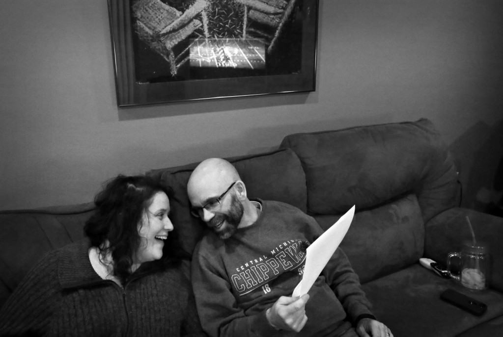 Jennifer and Dan Digmann read over a classroom presentation they are giving to physical therapy students while watching a Lions football game at their home in Mount Pleasant, Mich.